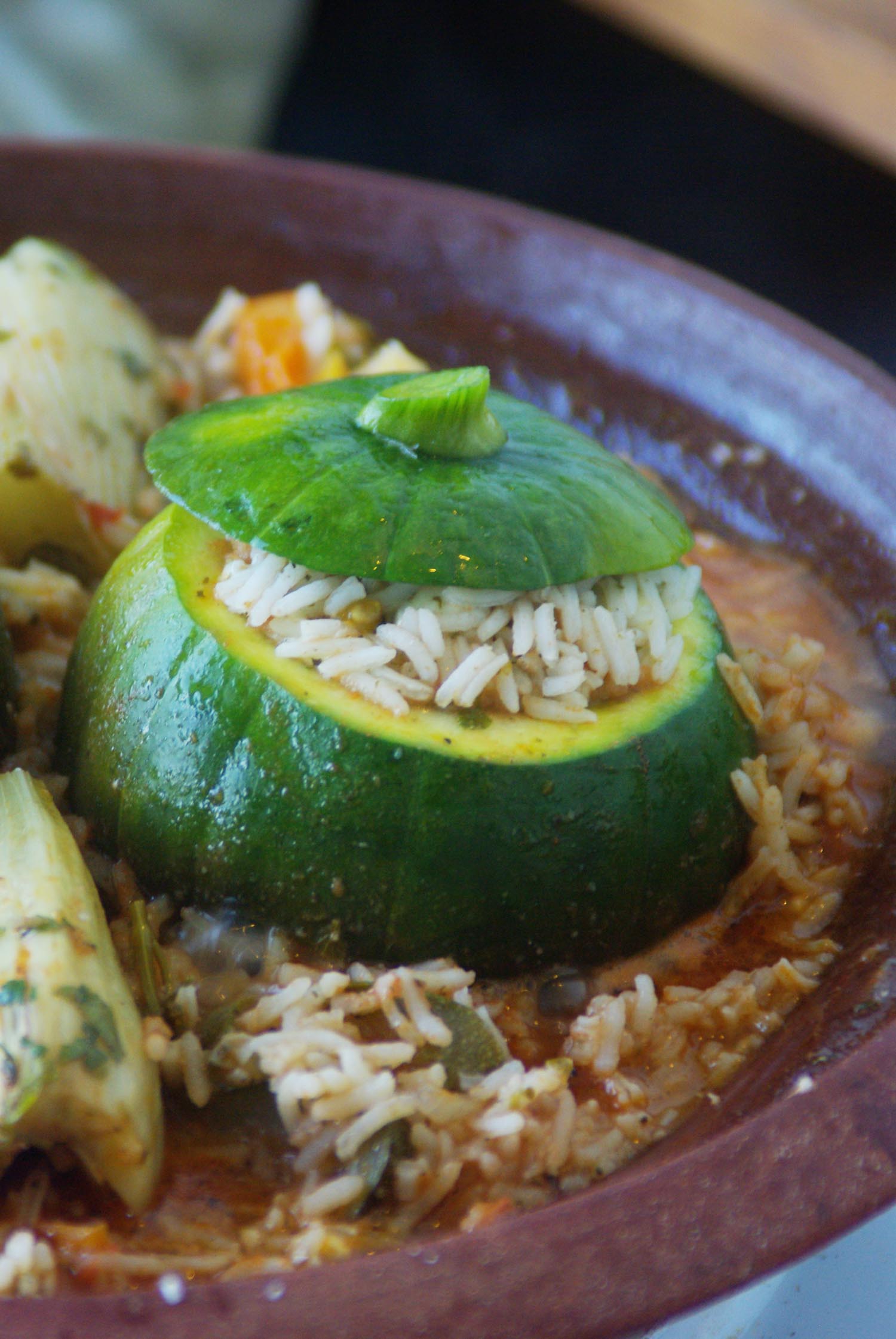 Ein gefüllter Zappo = runde Zucchini. Außen grün, innen gelblich. Ausgehöhlt und mit Reis gefüllt. Im Unterteiol einer traditionellen Tajine angerichtet.